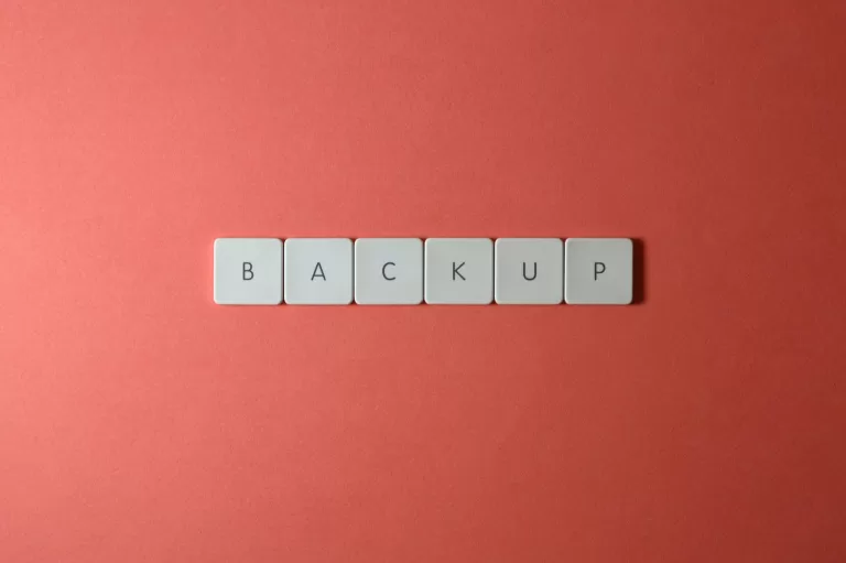 Free Close-up of keyboard keys spelling 'BACKUP' placed on a coral-colored surface. Stock Photo
